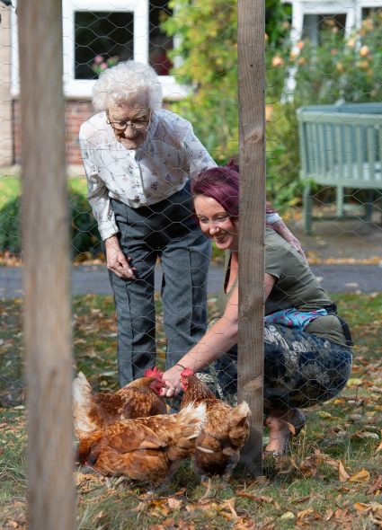 Resident and staff member with chickens at Connaught Court