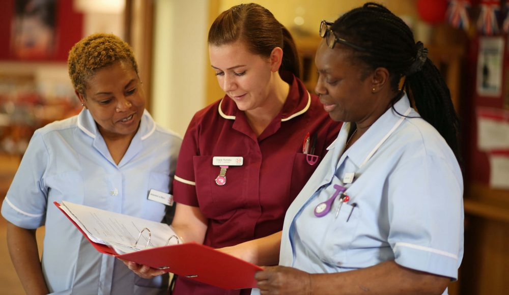 Group of RMBI Care Co. Nurses reading notes on a clipboard