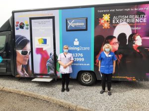 Albert Edward Prince of Wales Court’s staff members Kay Grist and Lisa Davies with the Dementia Bus, where they received dementia training and experienced what it feels like to live with dementia.