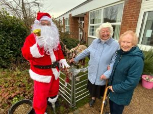 Cheerful residents Audrey Turner and Joan Watts meeting Father Christmas and George the reindeer at RMBI Home Devonshire Court
